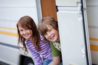zwei kinder sitzen am wohnwagen