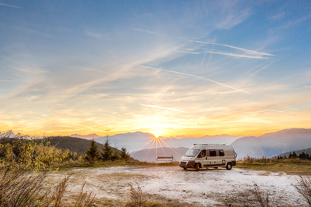 Wohnmobil vor Berglandschaft bei Sonnenuntergang