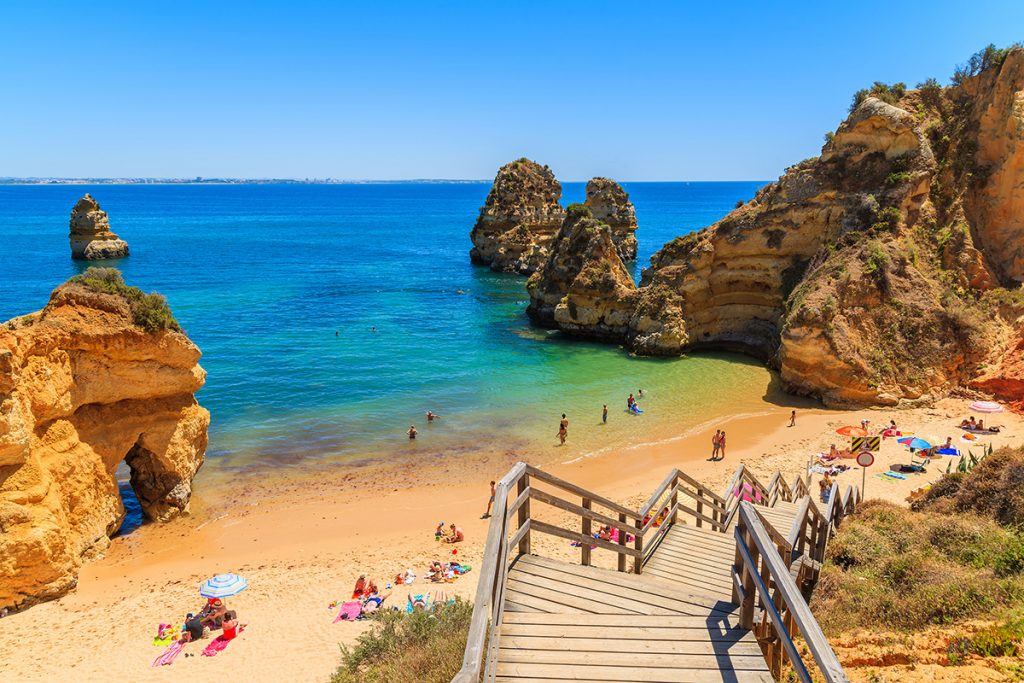 Ein Strand an blauem Wasser und großen Felsen in der Algarve.