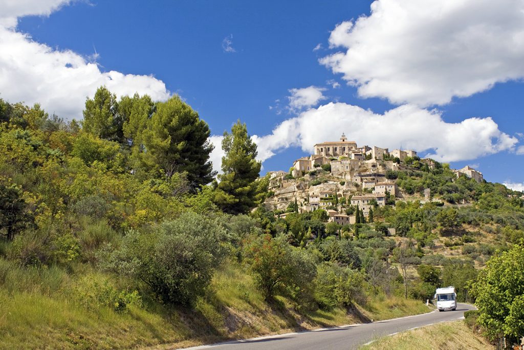 Die Provence mit dem Wohnmobil entdecken Straße mit Wohnmobil vor Gordes, Frankreich.