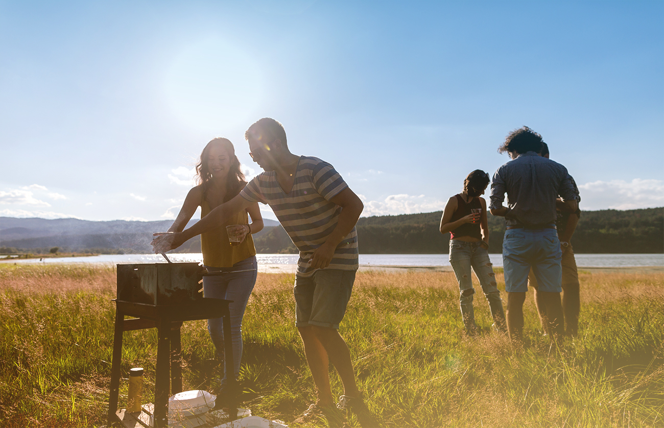 Freunde grillen bei Sonnenuntergang am See