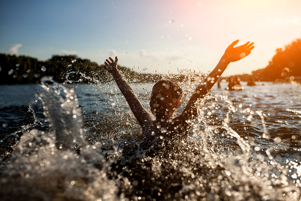 Kind badet im See bei Sonnenuntergang