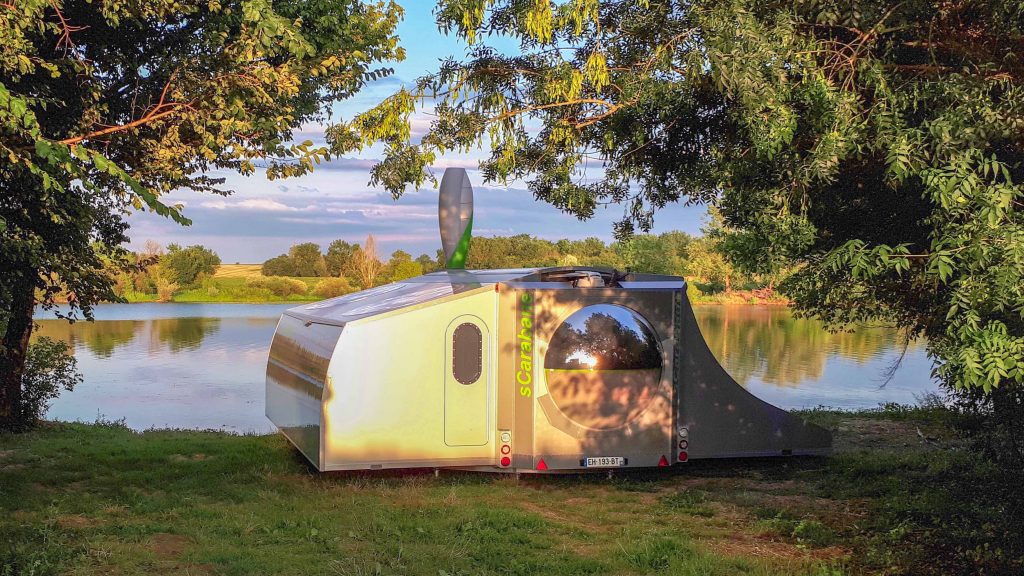 Der Wohnwagen sCarabane von Green Cat Technologies steht ausgeklappt am See.