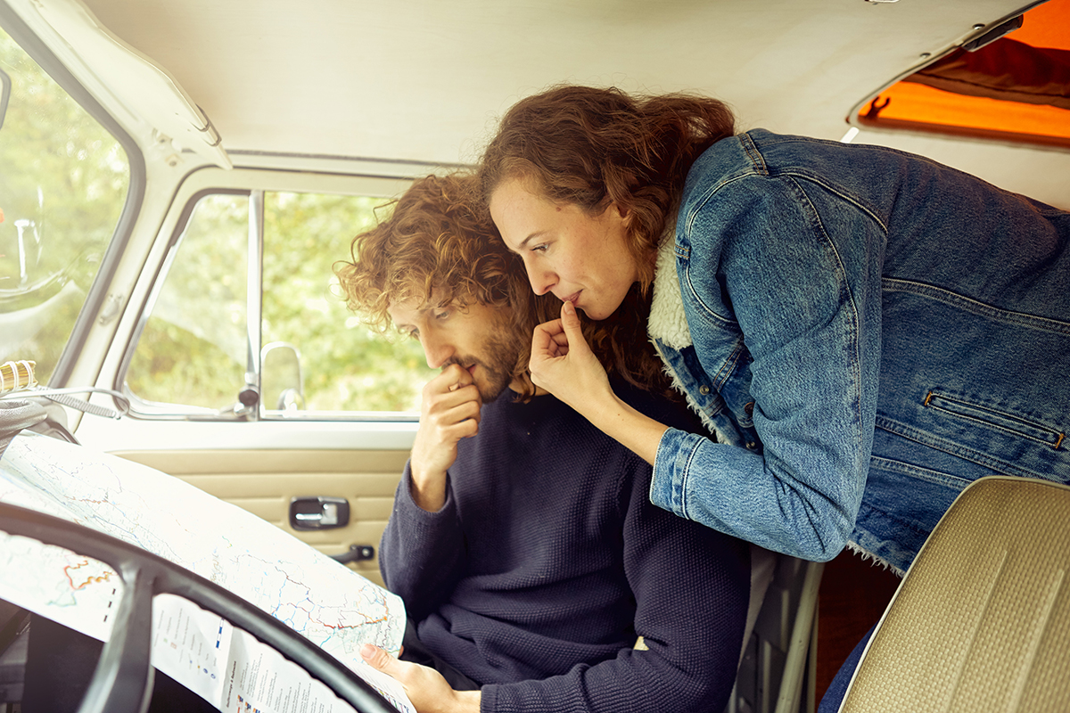 Planung für eine Wohnmobilreise durch Europa Pärchen mit Landschaftskarte in der Fahrerkabine eines Campers.