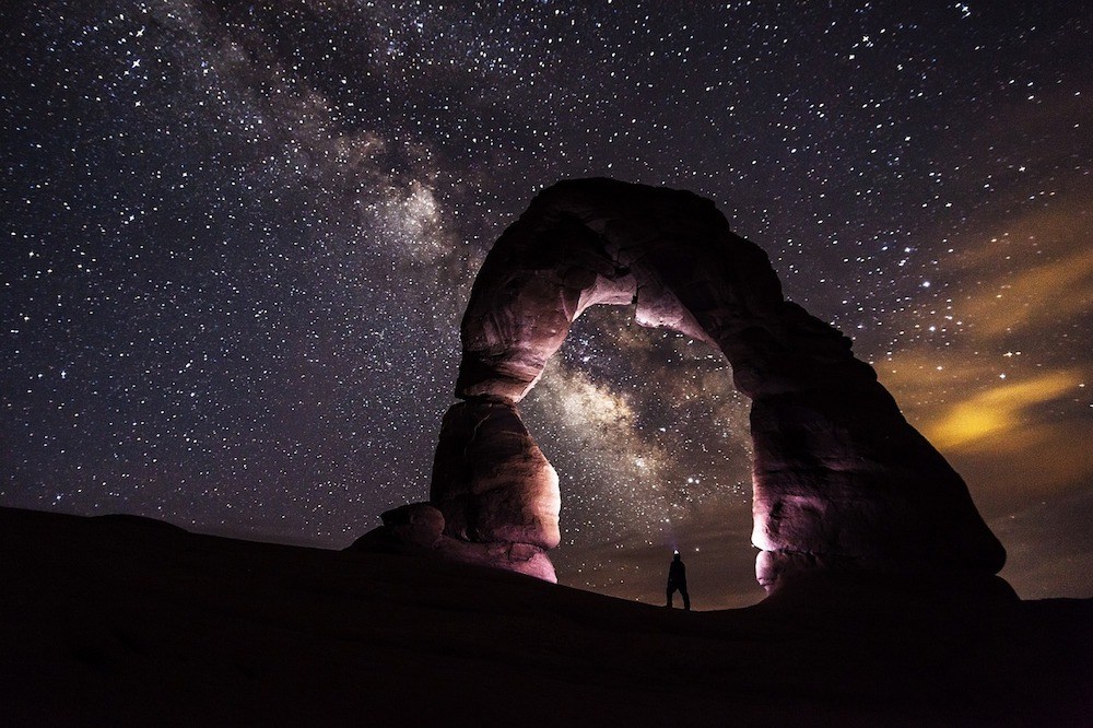 Ein Felsenbogen vor einem Sternenhimmel im Arches Nationalpark.