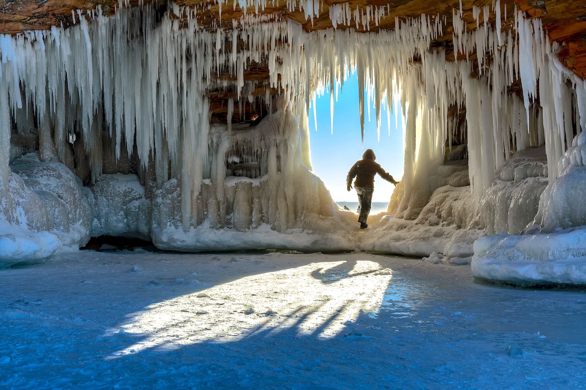 Eine Person in einer, von riesigen Eiszapfen verzierten, Höhle.