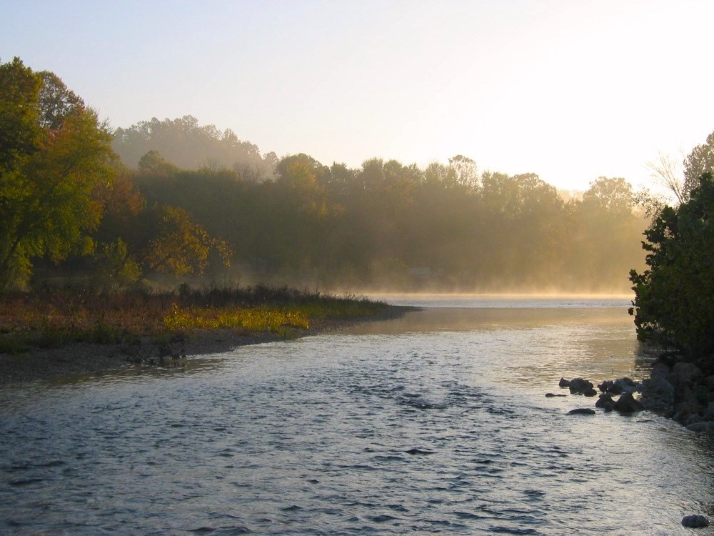 Ein von Bäumen gesäumter Fluss bei Sonnenaufgang im Ozark National Scenic Riverways.