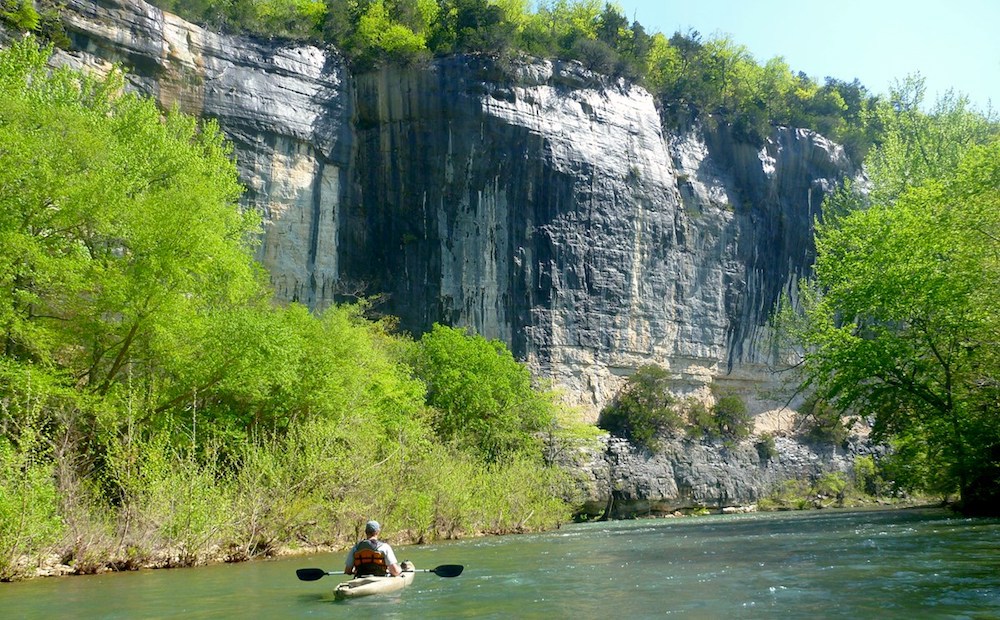 Ein Mann im Kajak auf dem Buffalo River, vor einem felsigen Steilufer.