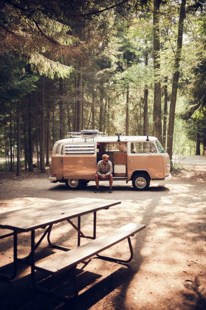 Mann sitzt in einem geparkten Camper in einem Wald.