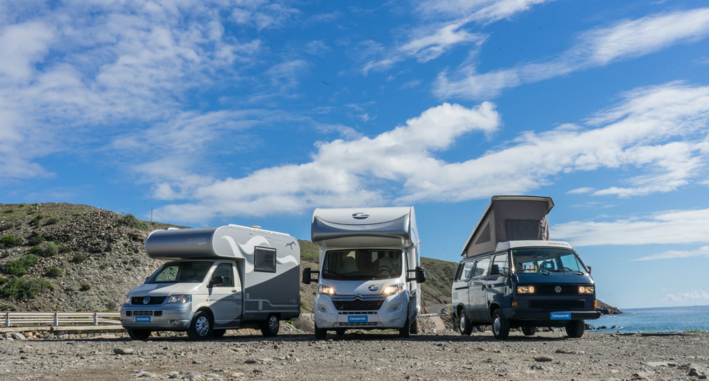 Zwei Alkoven Wohnmobile stehen neben einem VW-Campervan.