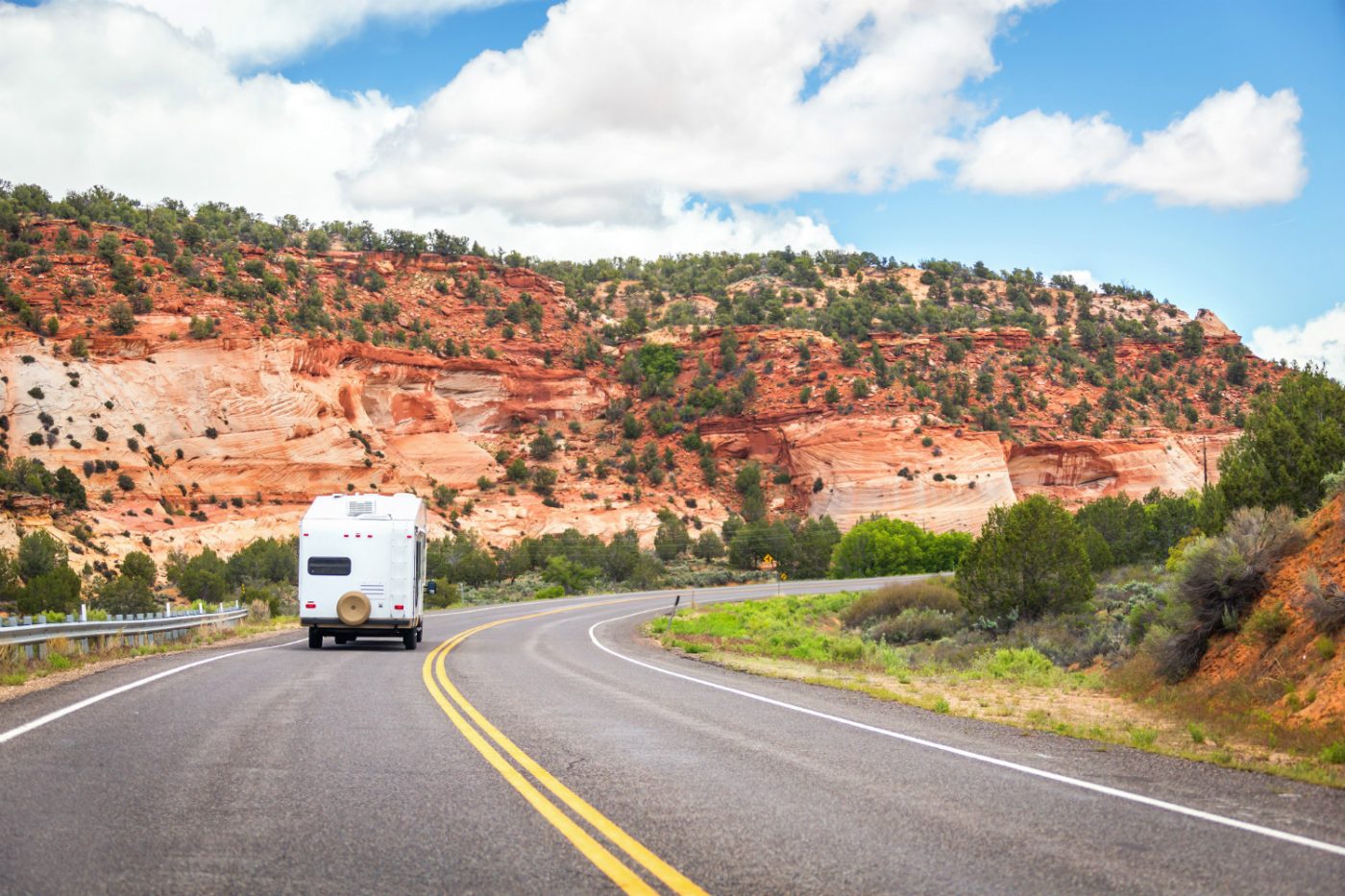 Die einzigartige und diverse Natur der USA mit dem Wohnmobil erkunden Wohnmobil fährt entlang roter Felsen in den USA