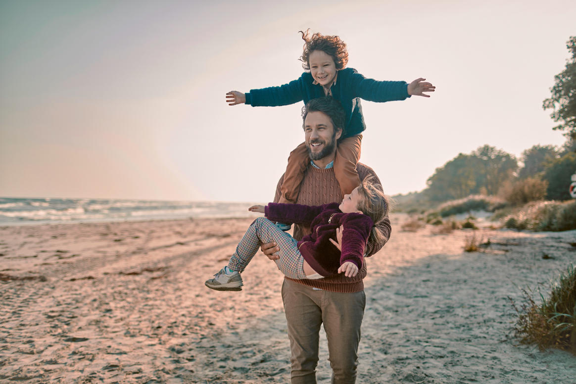 Ein Mann und zwei Kinder am Strand.