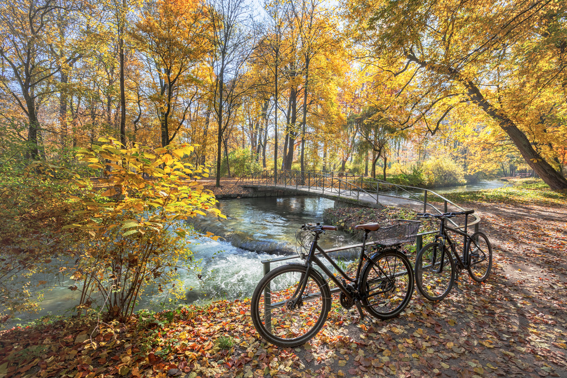 Zwei Fahrräder am Fluss im herbstlichen Englischen Garten in München.