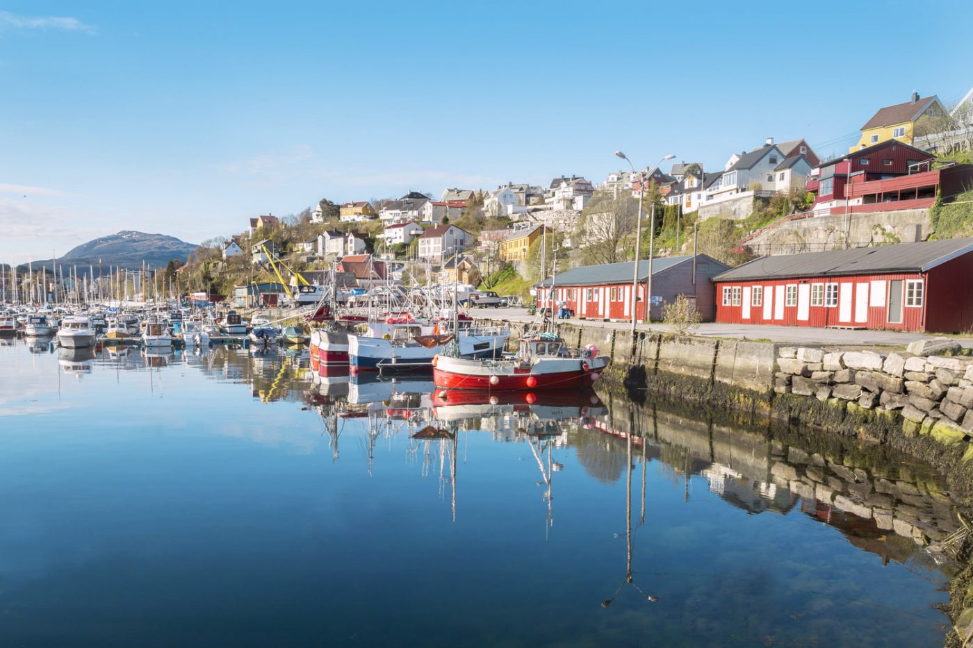 Auf der Wohnmobiltour durch Norwegen geht es ganz in den Süden: Nach Kristiansand. Der Hafen von Kristiansand mit vielen kleinen Booten und zahlreichen bunten Häuschen im Hintergrund.
