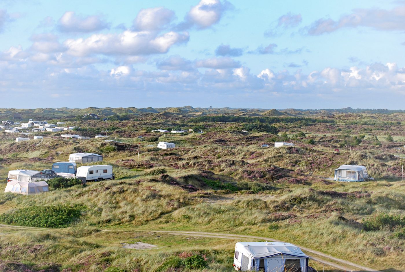 Wohnwagen und Zelte zwischen Dünen in Dänemark.