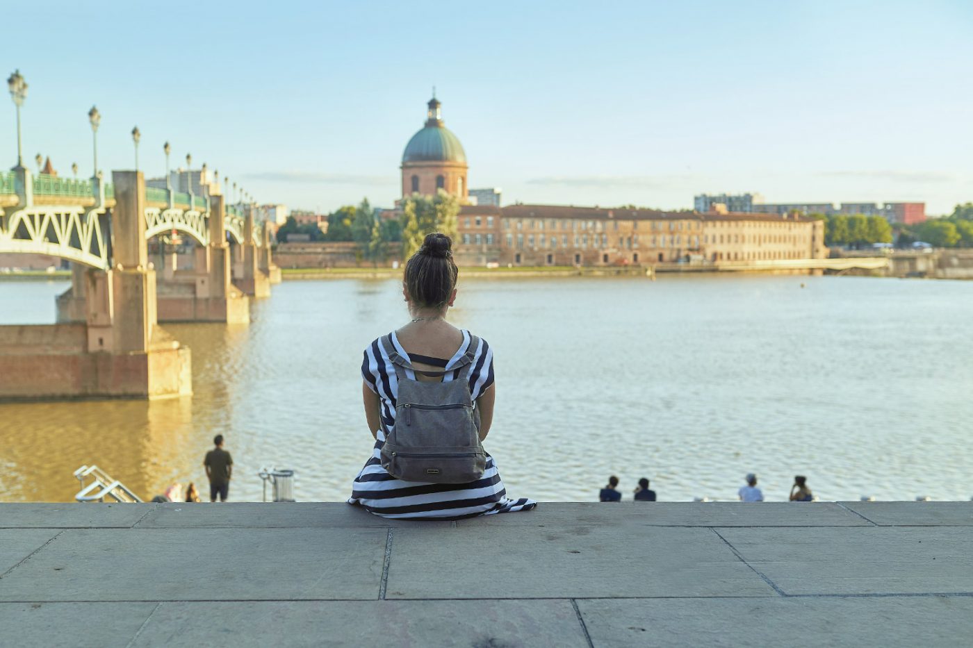 Eine Frau sitzt am Ufer des Fluss Garonne in Toulouse, Frankreich.