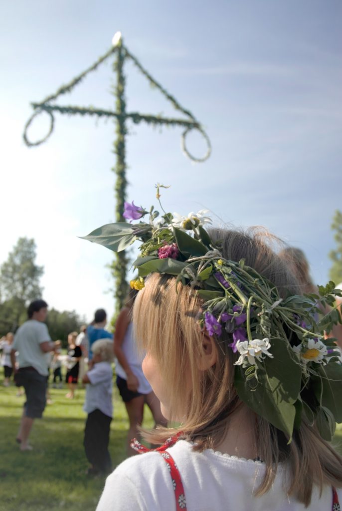 Ein blondes Kind mit einem Blumenkranz bei einem Midsommar-Fest.