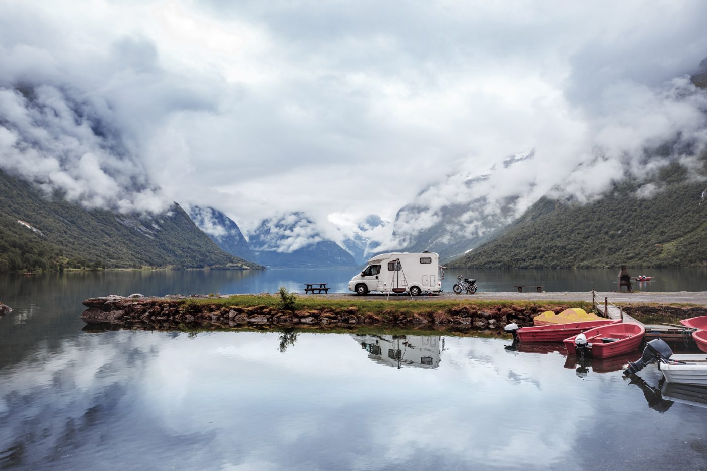 Mit dem Wohnmobil zum Camping nach Norwegen zu fahren, ist für viele ein wahrgewordener Traum. Ein Wohnmobil steht vor der beeindruckenden Kulisse eines Fjordes in Norwegen.