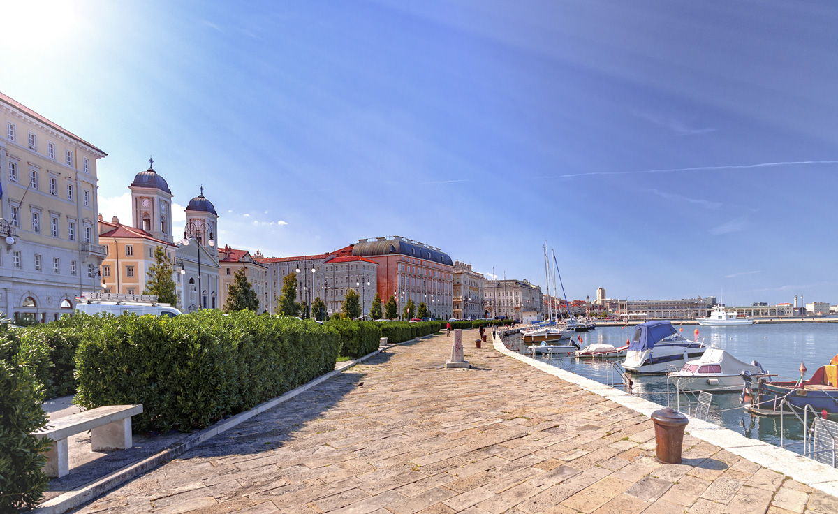 Boote und Häuser am Ufer in Triest, Italien. 