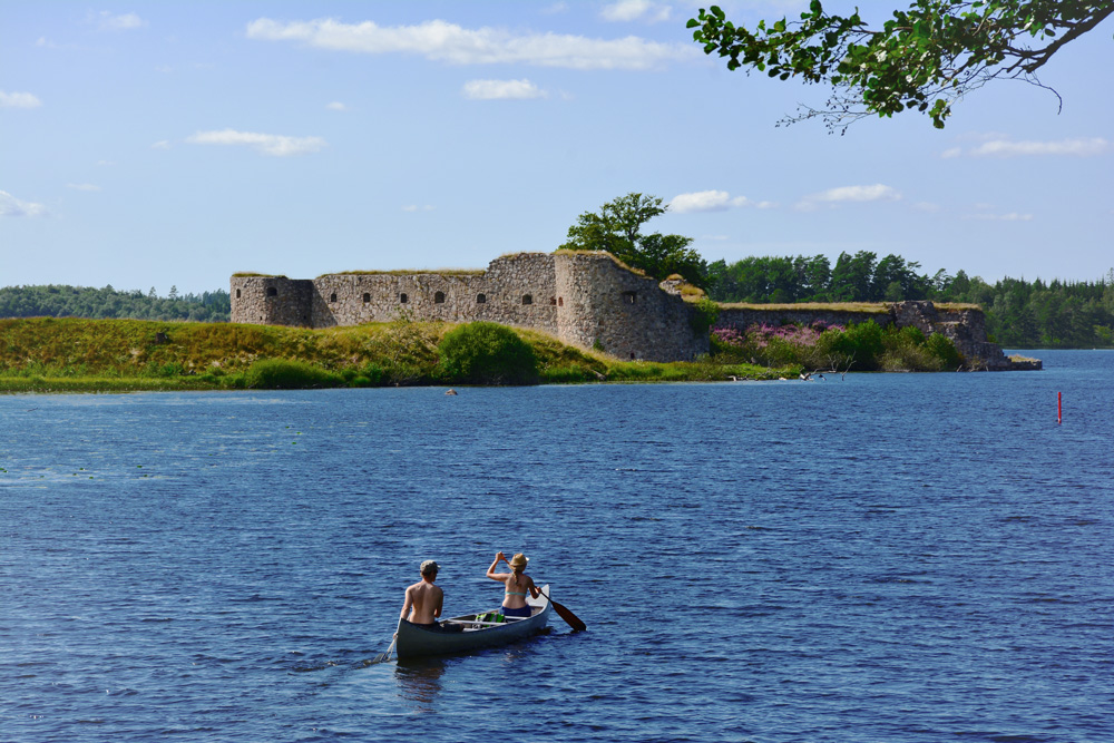 Zwei Kanu-Fahrer vor der Schlossruine Kronoberg bei Växjö, Schweden.