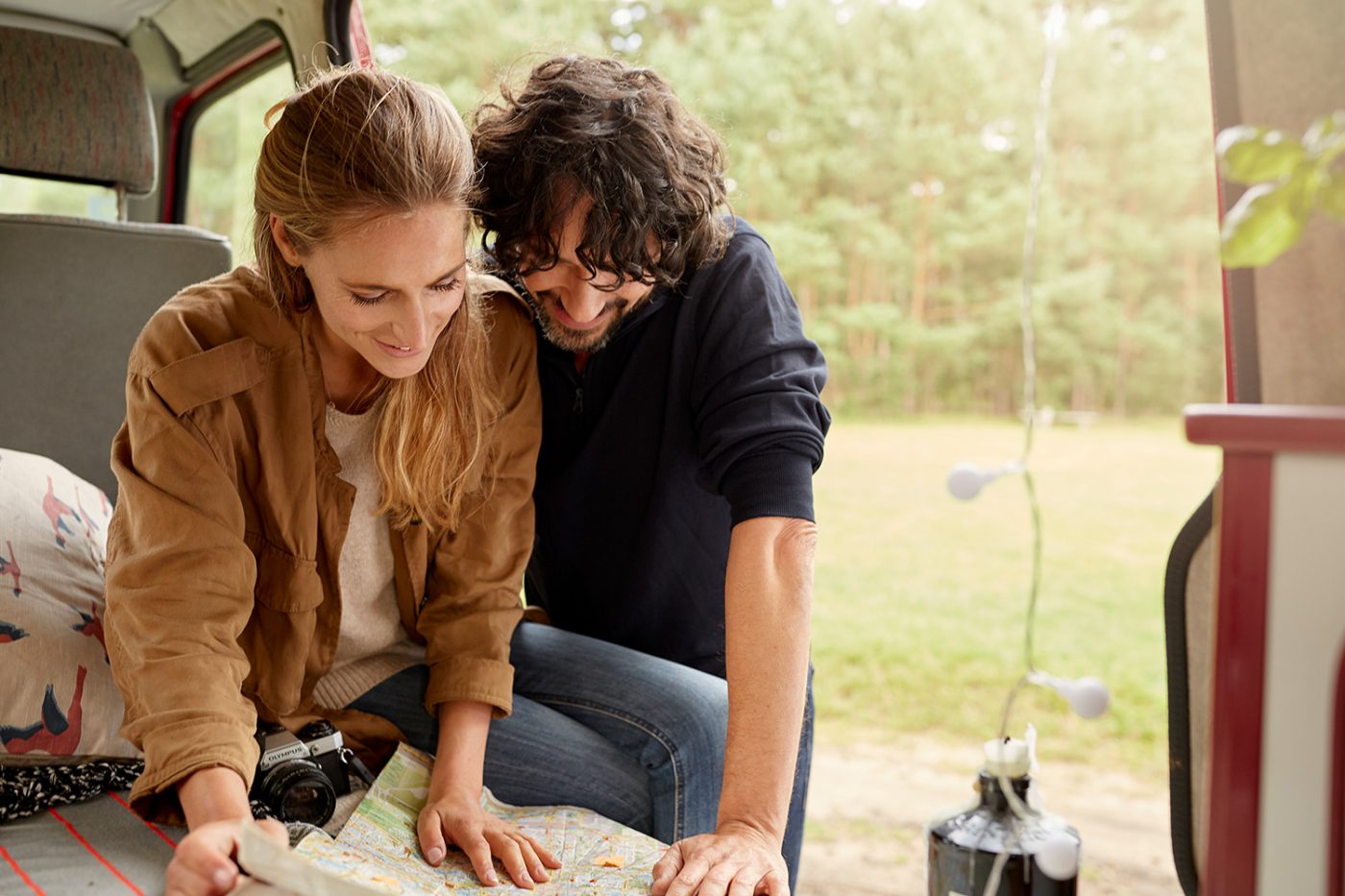 Planung für eine Wohnmobilreise durch Europa Pärchen mit Landschaftskarte in einem Camper.