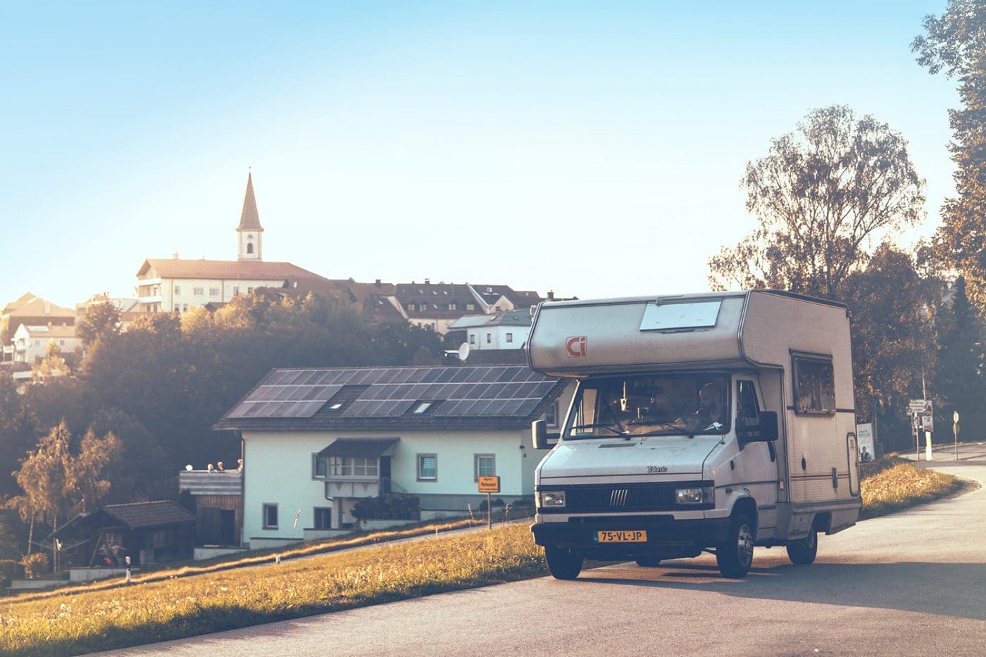 Mit einer guten Wohnmobilversicherung unterwegs. Ein Wohnmobil auf einer Straße in oder nahe einer Ortschaft.