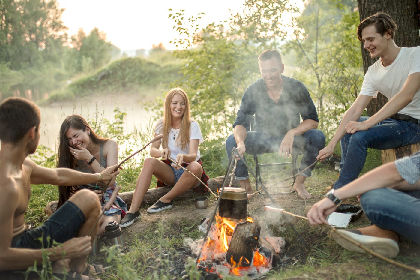 Eine Gruppe junger Menschen sitzt um ein Lagerfeuer.