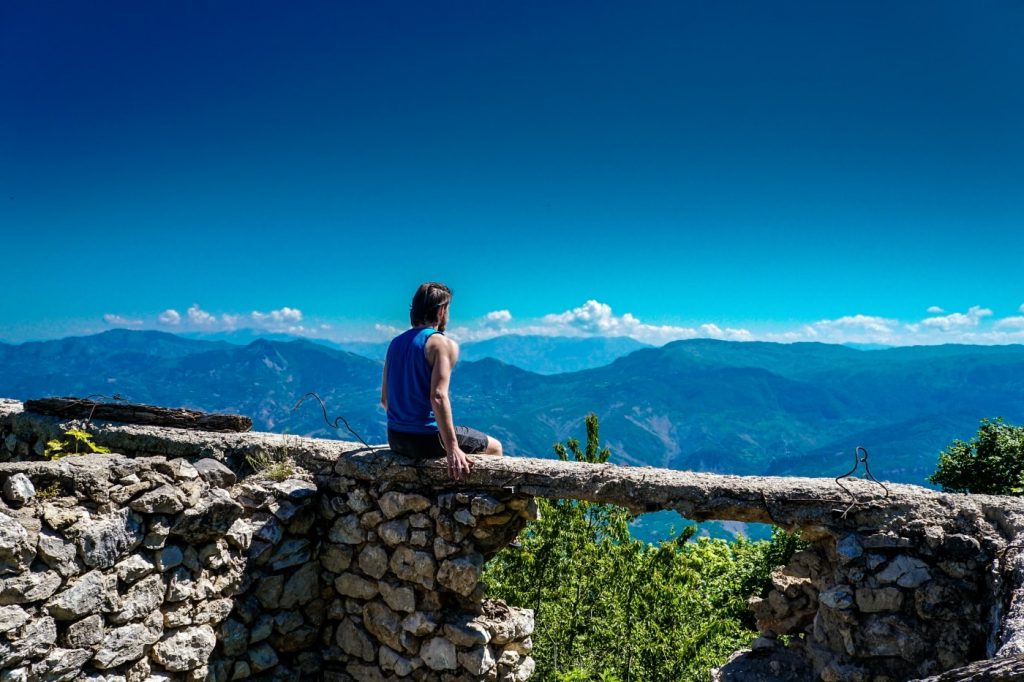 Mann auf Baumstamm in den Albanischen Alpen