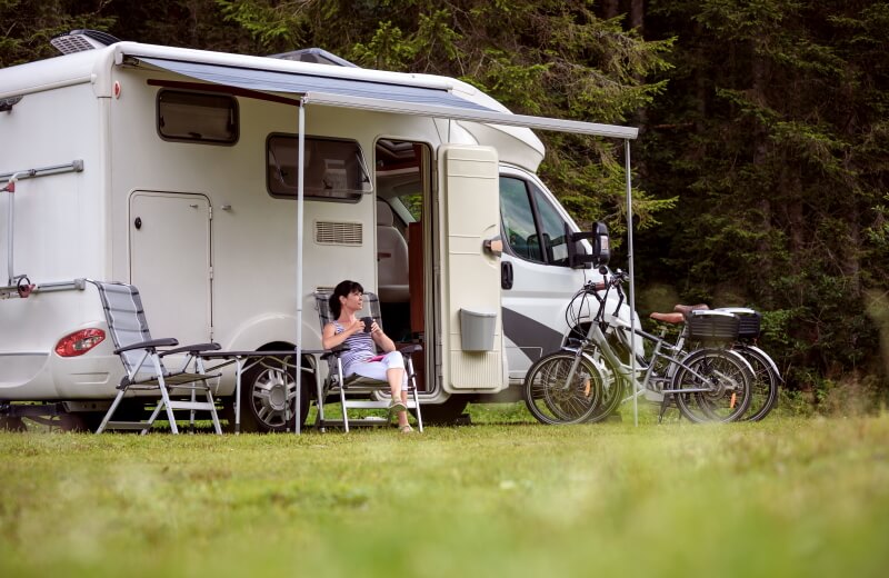 Frau trinkt Kaffee vor Wohnmobil