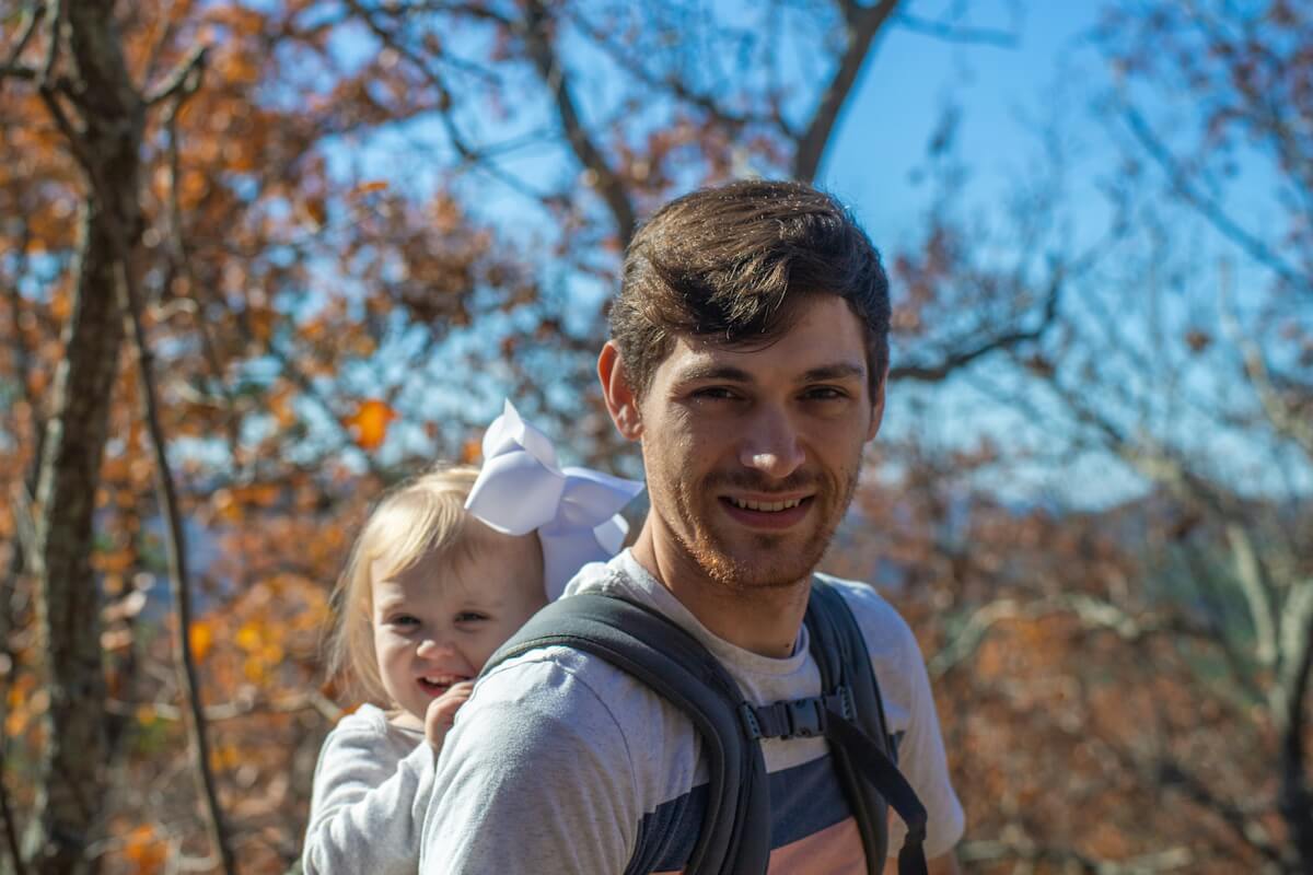 Junger Vater in der Natur mit Baby auf dem Rücken