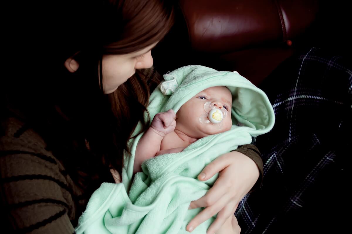 Baby mit Schnuller in grüner Kuscheldecke